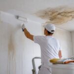 Peintre repeignant un mur après un dégât des eaux